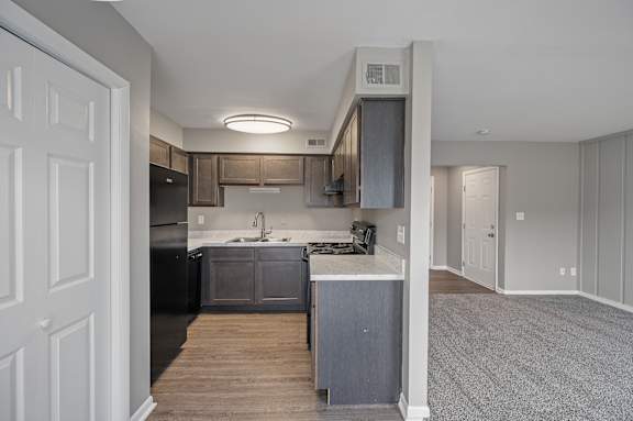 A kitchen with a black fridge and a white door.