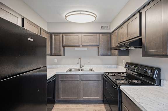 A kitchen with a black refrigerator and a black stove top oven.