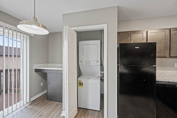 A black refrigerator is in a kitchen with a white fridge in the background.