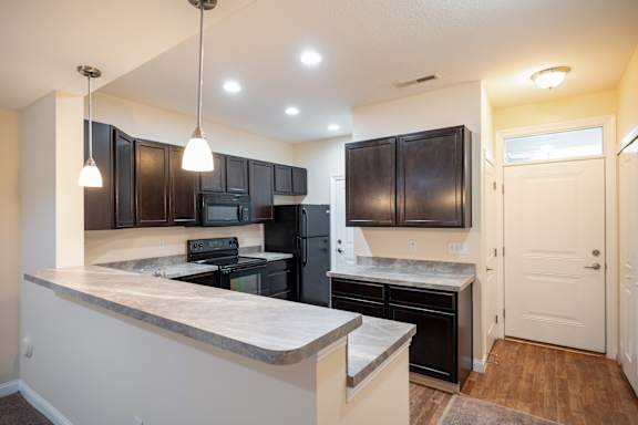 A kitchen with black cabinets and a white door.