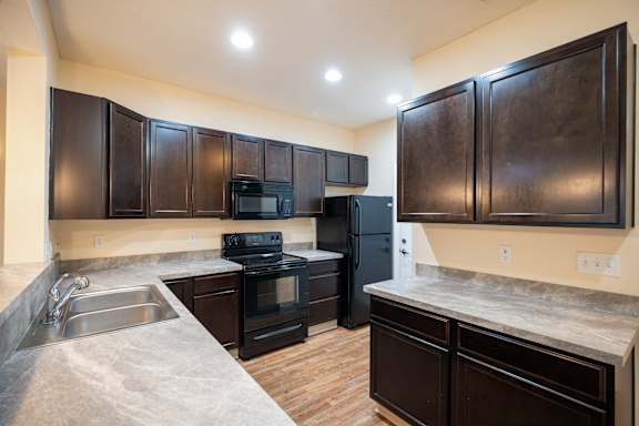A kitchen with dark brown cabinets and a black stove top oven.