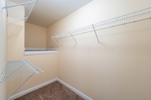 A room with a brown carpet and a white ceiling with a metal shelf on the wall.