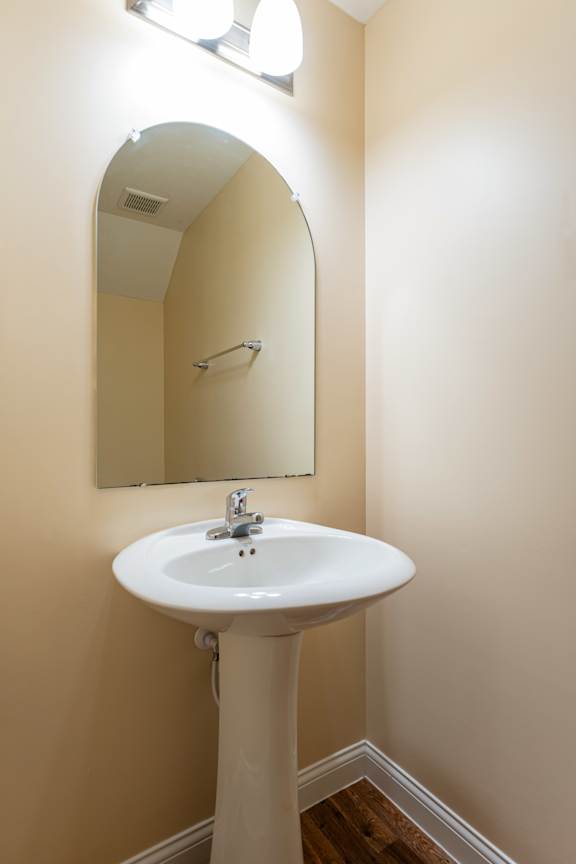 A white pedestal sink with a mirror above it.