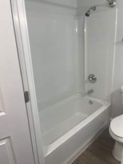 A white toilet sits next to a white bathtub in a bathroom.