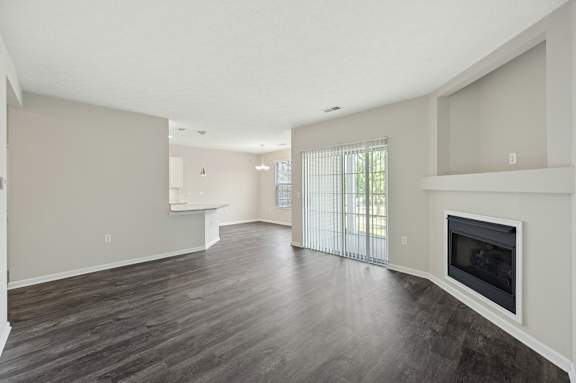 A spacious living room with a fireplace and a large window.