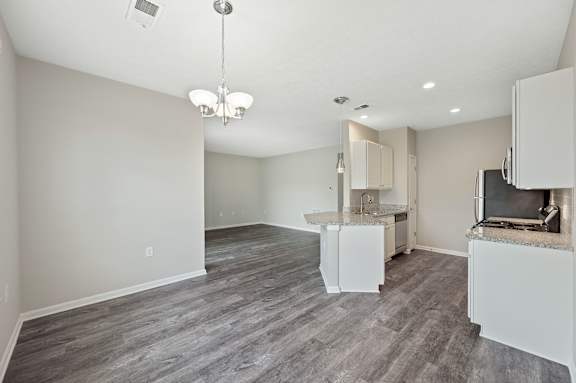 A spacious living room with a grey floor and a chandelier hanging from the ceiling.
