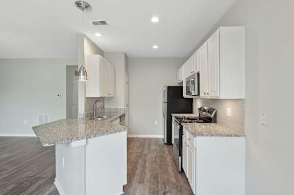 A kitchen with white cabinets and a granite countertop.