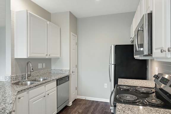 A kitchen with white cabinets and a black refrigerator.