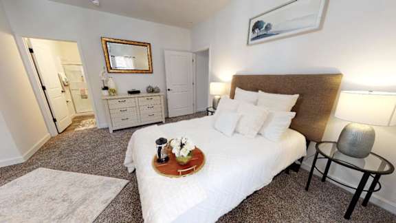 A bedroom with a large bed, a dresser, and a chair.
