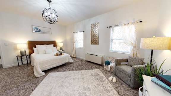 A bedroom with a bed, a couch, and a rug.