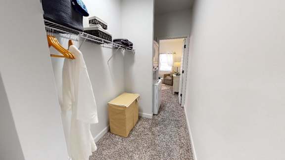 A white coat hanging on a rack in a room.