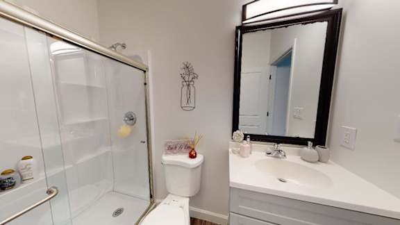 A bathroom with a white sink and a glass shower stall.