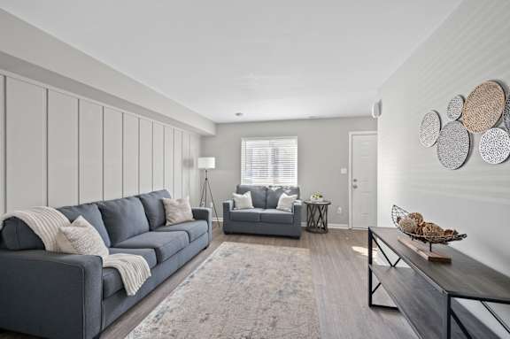 A grey couch with pillows and a blanket sits in a room with a grey wall and a wooden coffee table. at The Parkton, Cincinnati, OH