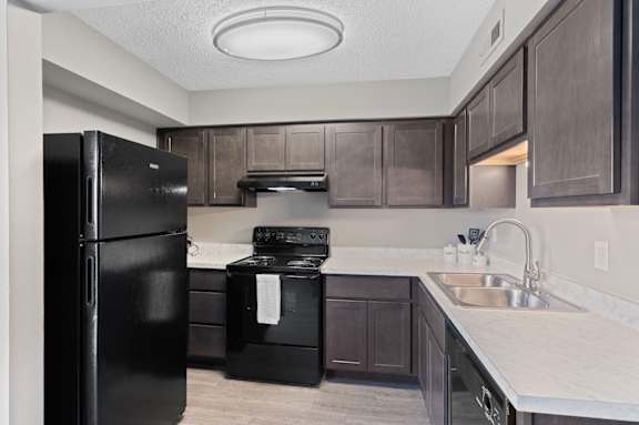 A kitchen with black appliances and brown cabinets. at The Parkton, Cincinnati, 45231