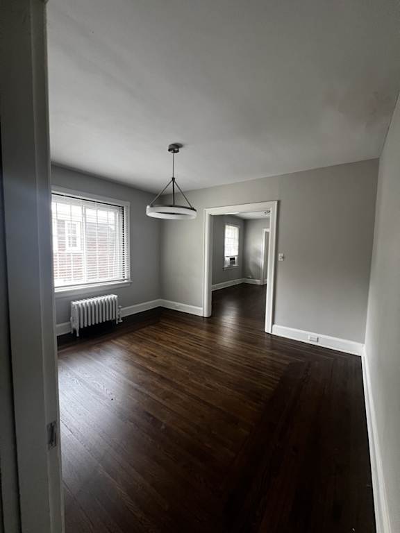 A room with wooden floors and a hanging light fixture.
