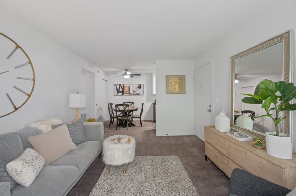 the living room and dining room of an apartment with a couch and a mirror