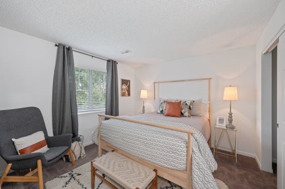 a bedroom with a bed and a chair and a window