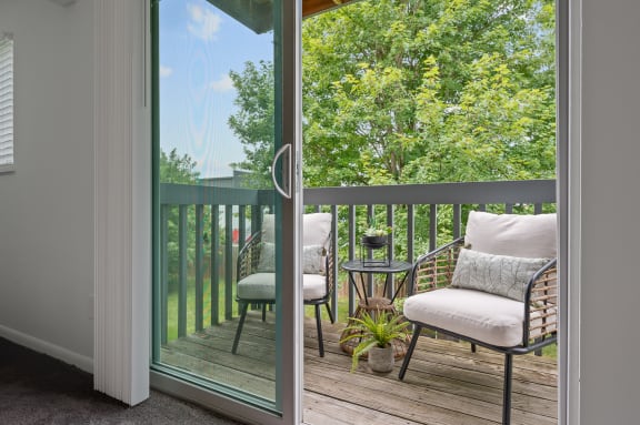 a balcony with two chairs and a table and a sliding glass door