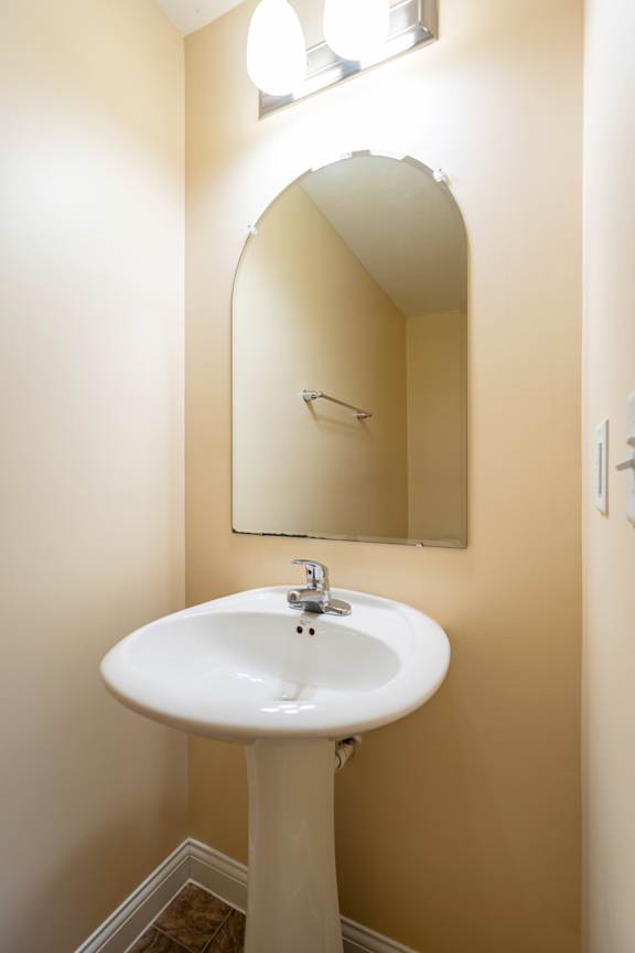 A white pedestal sink with a mirror above it.