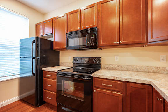A kitchen with brown cabinets and black appliances.