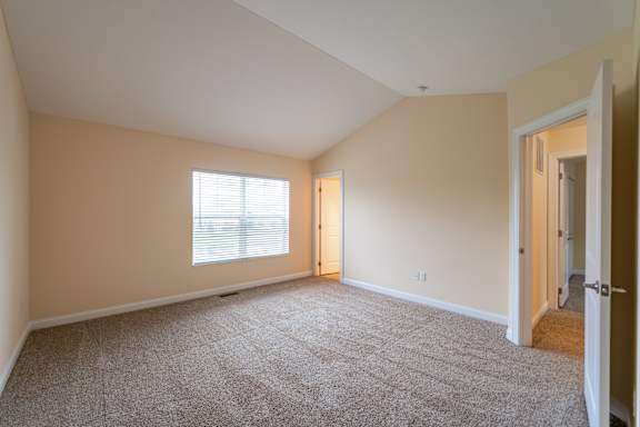 A room with a carpeted floor and two windows.