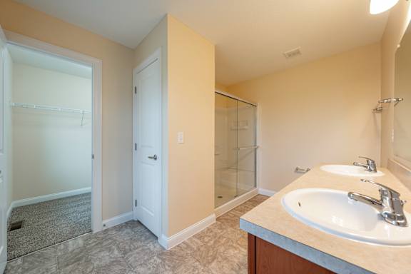 A bathroom with a sink, mirror, and shower.