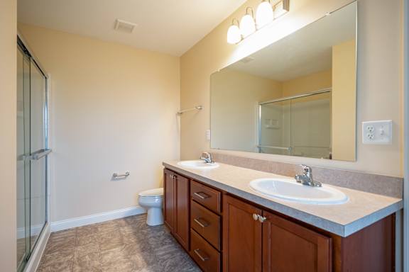 A bathroom with a sink, toilet, and mirror.