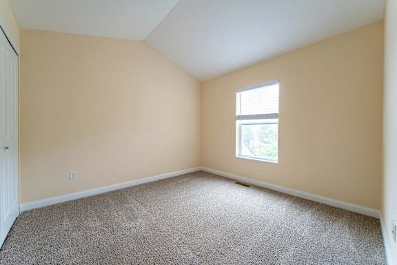 A room with a carpeted floor and a window letting in natural light.