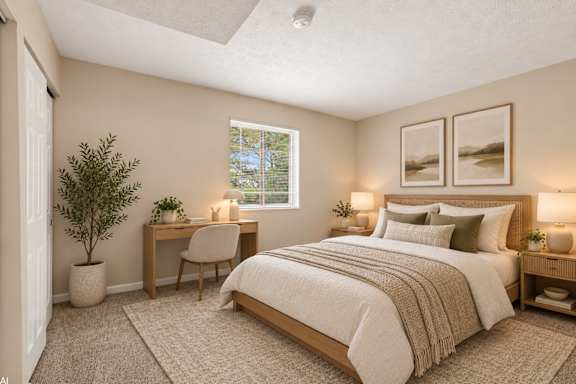 A bedroom with a large bed, a desk with a chair, and a potted plant.