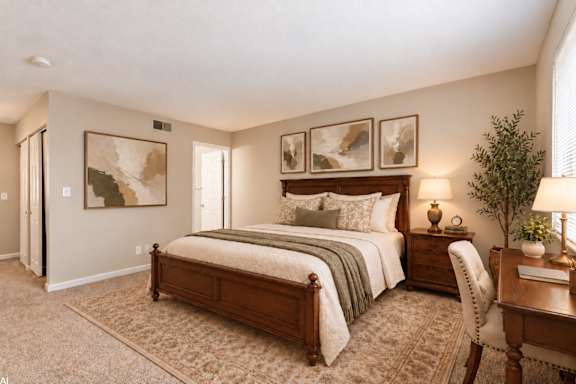 A bedroom with a large bed and a smaller bed with a desk and chair.