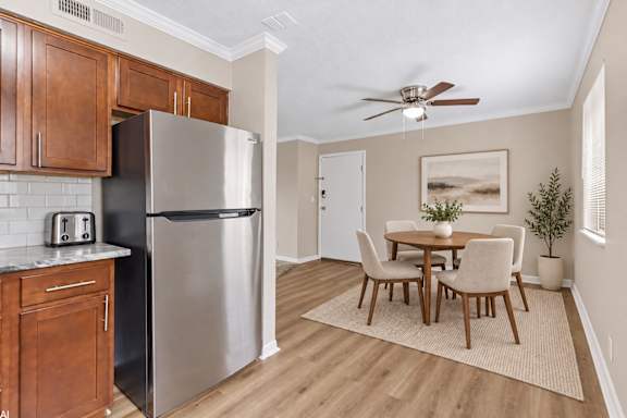 A kitchen with a refrigerator, toaster, and wooden cabinets.