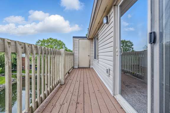 A wooden deck with a sliding glass door leading to a backyard.