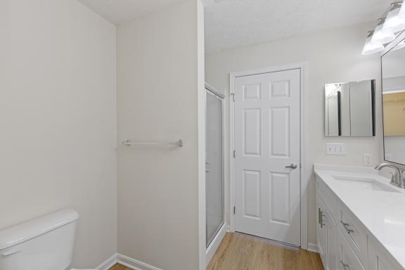 A white bathroom with a toilet, sink, and shower.