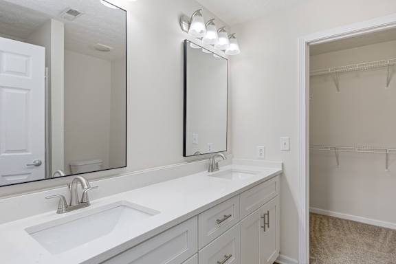A bathroom with a sink, mirror, and lighting fixture.