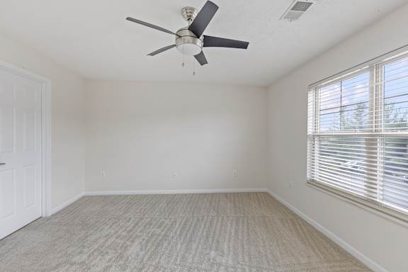 A room with a ceiling fan and carpeted floor.
