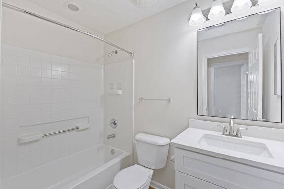 A white bathroom with a toilet, sink, and bathtub.