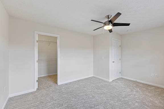 A room with a ceiling fan and carpeted floor.
