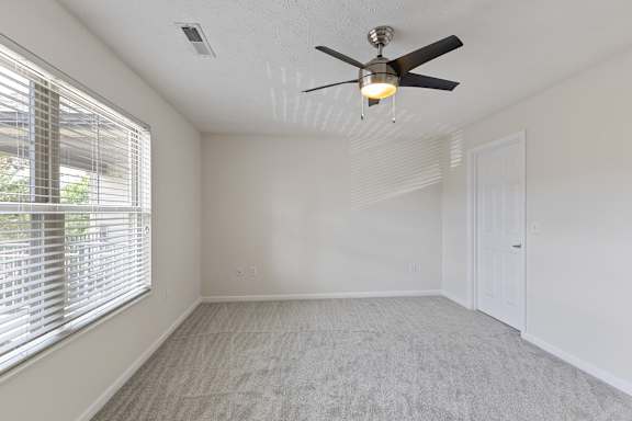 A room with a ceiling fan and a window with blinds.