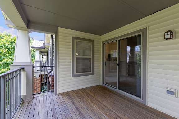 A white house with a wooden deck and sliding glass doors.