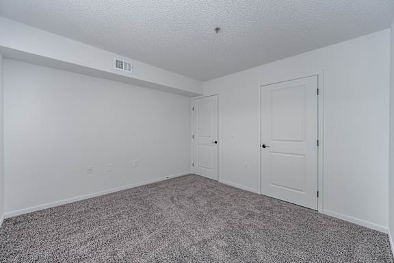 A room with a carpeted floor and three doors.