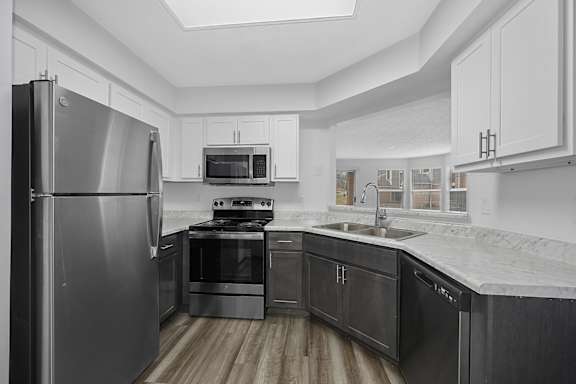 A modern kitchen with a stainless steel refrigerator and black countertops at Indian Lookout Apartments, West Carrollton, Ohio