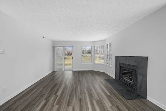 A large empty room with a fireplace and wood flooring at Indian Lookout Apartments, West Carrollton, OH, 45449