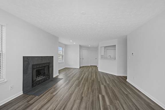 A room with a fireplace and wood flooring at Indian Lookout Apartments, West Carrollton