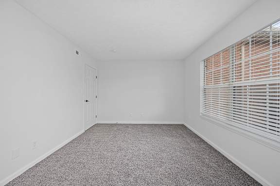 A room with a carpeted floor and a window with blinds at Indian Lookout Apartments, Ohio, 45449