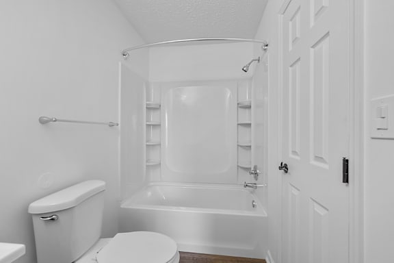 A white bathroom with a toilet, tub, and shower at Indian Lookout Apartments, West Carrollton, 45449