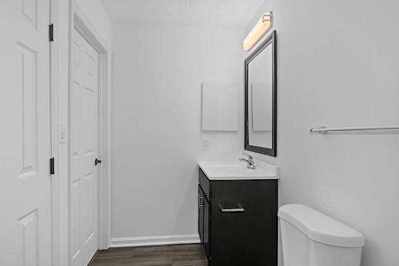A bathroom with a white toilet and a sink with a mirror above it at Indian Lookout Apartments, West Carrollton, OH, 45449