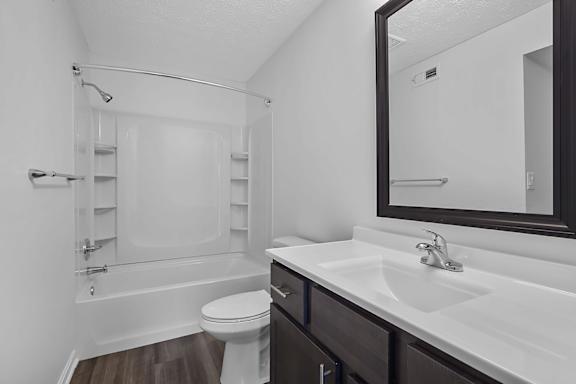 A white toilet sits in a bathroom next to a sink at Indian Lookout Apartments, West Carrollton, Ohio