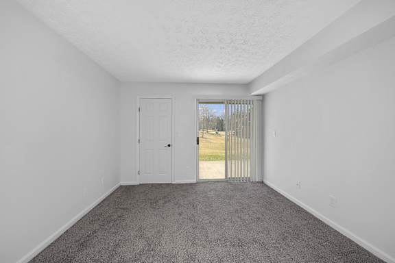A room with a white door and carpeted floor at Indian Lookout Apartments, West Carrollton, Ohio