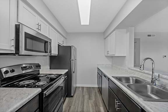 A modern kitchen with a stove, microwave, refrigerator, and sink at Indian Lookout Apartments, West Carrollton, Ohio