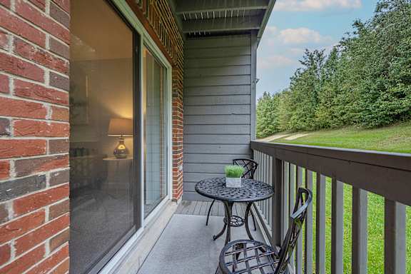 A balcony with a table and chairs overlooking a grassy area.